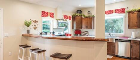 A kitchen with a bar area, wooden cabinets, a microwave, and a dishwasher.
