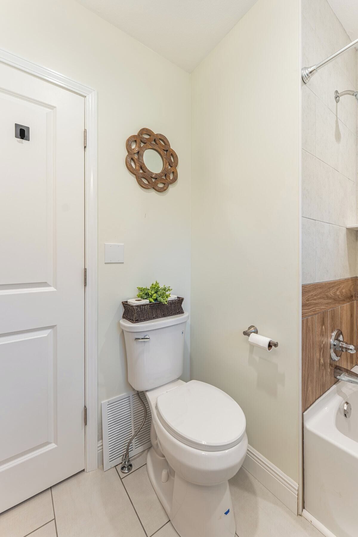 A bathroom with a toilet, a shower, and a decorative wall piece.