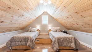 Een slaapkamer met twee bedden, een houten schuine kap en een dakraam.