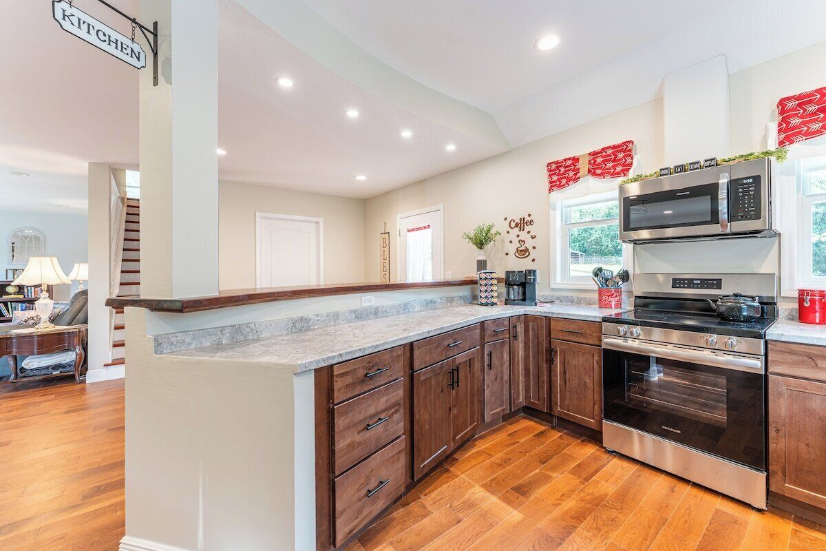 A kitchen with wooden cabinets, a stainless steel oven, a microwave, and a coffee station.