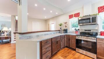 A kitchen with wooden cabinets, a stainless steel oven, a microwave, and a coffee station.