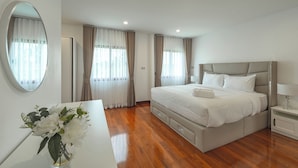 Una habitación de hotel moderna con una cama grande, una mesita de noche, un espejo y un jarrón con flores.