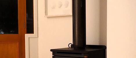 A room with a black wood-burning stove, a white sofa, and a framed picture on the wall.