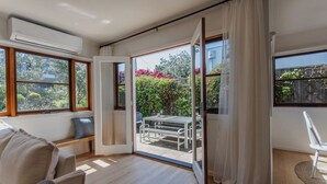 A modern room with a sliding glass door leading to an outdoor patio. - Chic Beachside Stay – Near River, Shops & Cafés (Ocean Grove)