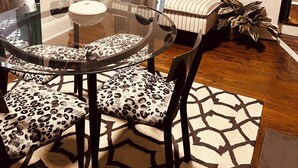 A living room with a glass table, leopard print chairs, a striped sofa, and a wall decorated with vinyl records. - Village District - Historic 2-bedroom house in Raleigh (Raleigh)
