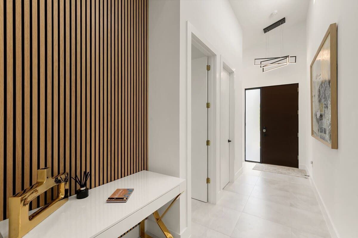 A hallway with a white console table, a wooden slat wall, and a door at the end.