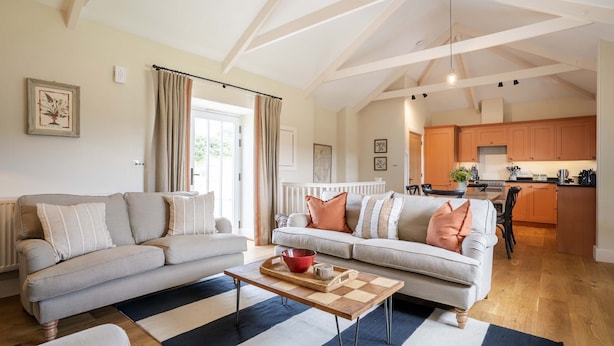 A spacious living room with a sofa, a coffee table, and a view into the kitchen. - Cowlands 3 bed, barn conversion, pet friendly, three bedrooms, Sleeps 6 (Truro)