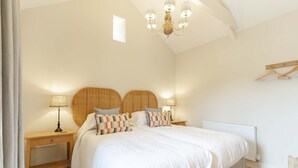 Ein Schlafzimmer mit einem großen Bett, zwei Nachttischen, einer Deckenleuchte und einer Heizung.
