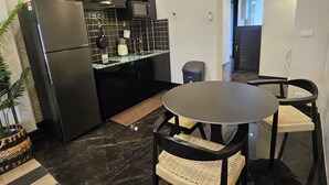 Una cocina moderna con un refrigerador negro, un microondas y un lavamanos. Hay una zona de comedor con una mesa redonda y dos sillas.