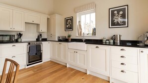 A modern kitchen with white cabinetry, a black countertop, and a built-in oven. There is a window with a view of the outside, and two framed pictures on the wall.