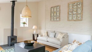 A cozy living room with a fireplace, a sofa, a coffee table, and decorative wall art.
