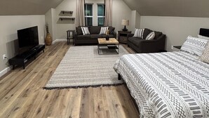 A spacious attic bedroom with a high ceiling, a ceiling fan, and recessed lighting.