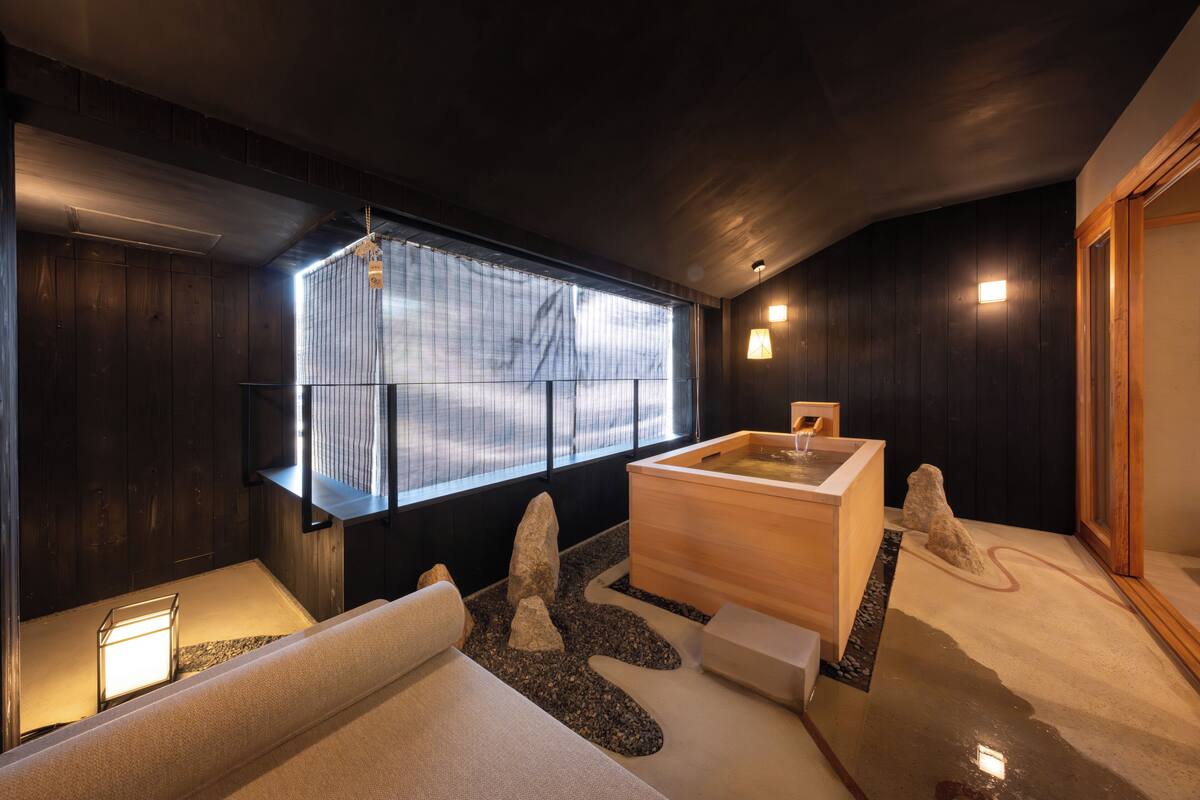 Ein moderner Spa-Bereich mit einer Holzwanne, einem Massagetisch und einem großen Fenster mit Blick.