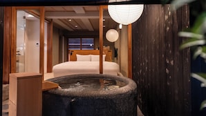 A traditional Japanese-style room with a bed, a wooden floor, a stone hot tub, and a wooden wall. - Nazuna Kyoto Nishi Honganji (Kyoto)