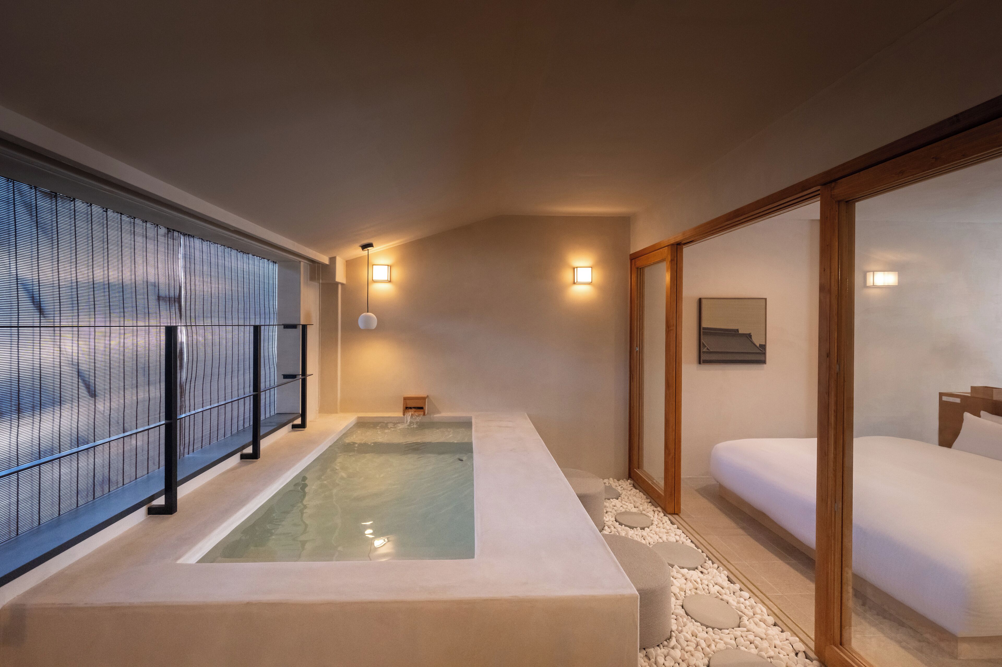 A spa room with a hot tub, a bed, and a wooden sliding door.