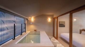 A spa room with a hot tub, a bed, and a wooden sliding door.
