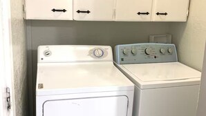 A laundry area with two white washing machines and cabinets above.