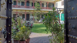 A courtyard with a paved walkway, potted plants, and a scooter. - Ikshana Boutique (Jaipur)