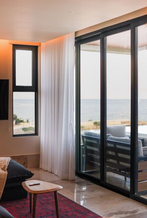 A hotel room with a large sliding glass door leading to a balcony with a view of the beach. - Distrito Puerto – Ocean & Mangrove Views (Puerto Morelos)