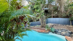 Una piscina rodeada de exuberante vegetación y una terraza de madera.