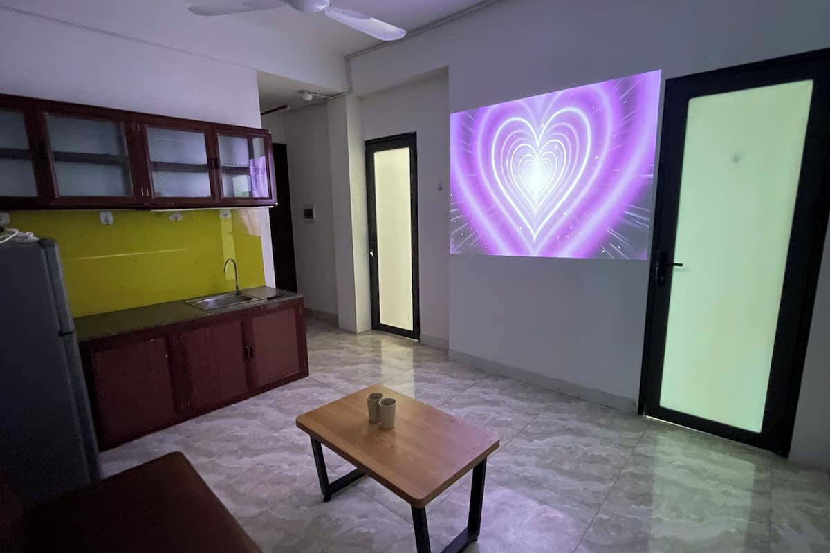 Una cucina moderna con zoccolo giallo, un tavolo di legno con due tazze e una parete ampia decorata con una luminosa forma a cuore.