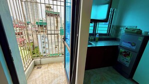 Une cuisine équipée d’un réfrigérateur, d’un évier et d’une fenêtre donnant sur un balcon.