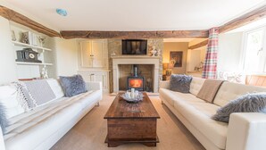 A cozy living room with a fireplace, white sofas, and a wooden coffee table.