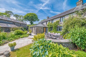 A stone house with a garden patio, outdoor seating, and a large tree. - A cottage that sleeps 10 guests  in 5 bedrooms (Grayrigg)