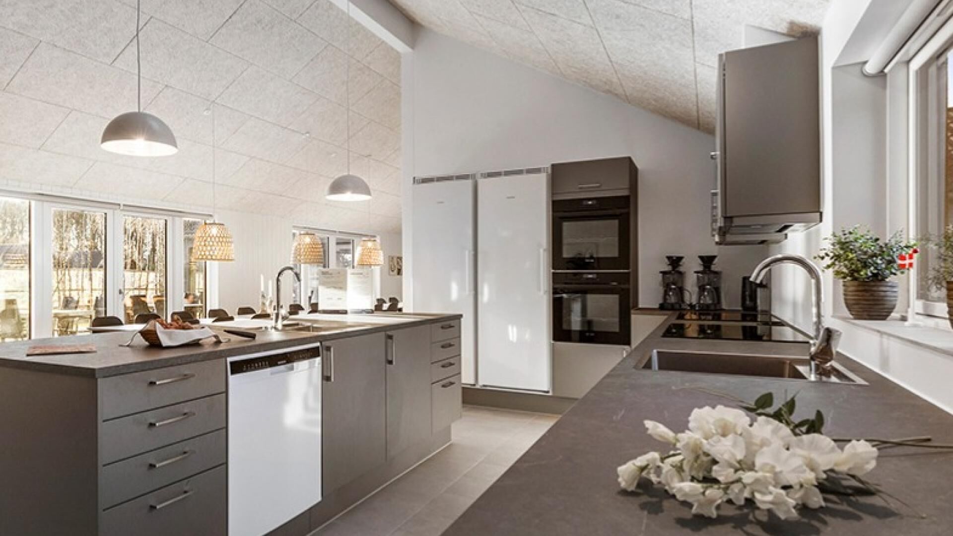 A modern kitchen with a large island, built-in appliances, and pendant lighting.