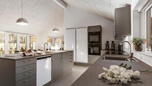 Una cocina moderna con una isla grande, electrodomésticos integrados e iluminación colgante.