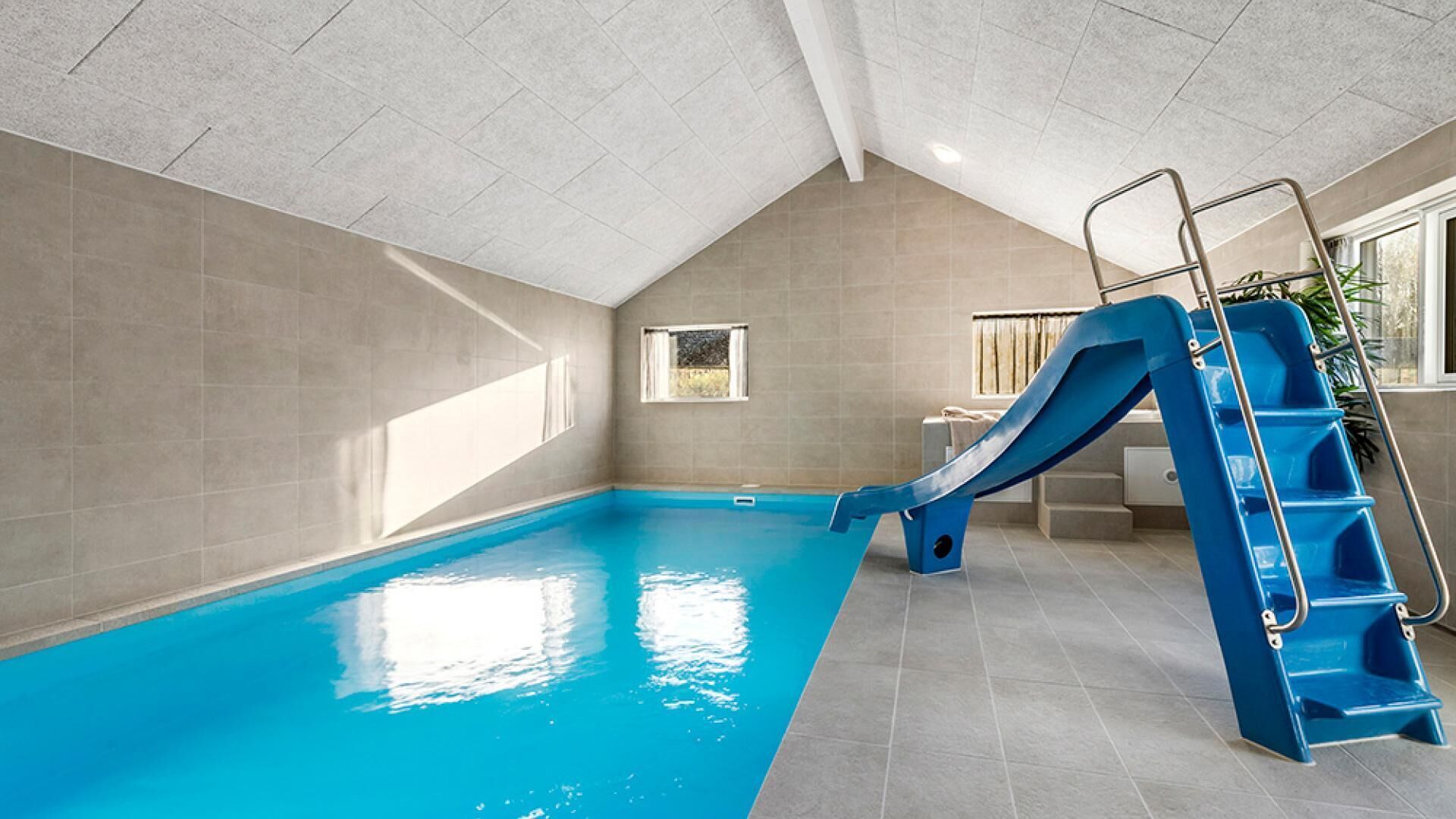Una piscina interior con un tobogán azul y una escalera.
