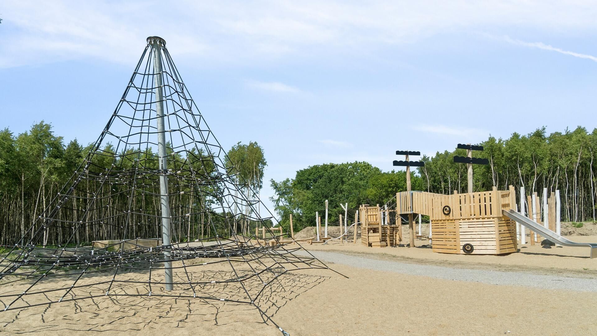 A playground with a climbing structure and wooden playhouses.