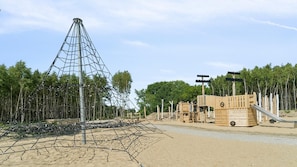 Ein Spielplatz mit Klettergerüst und Spielhäusern aus Holz.