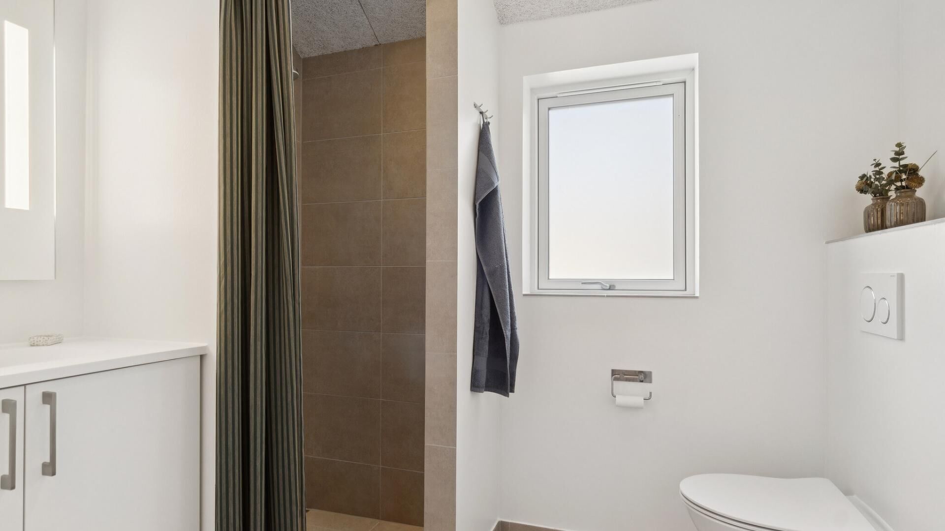 Un baño con inodoro, toallero, ventana y zona de ducha.
