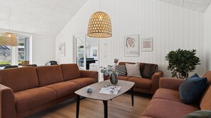 Ein modernes Wohnzimmer mit einer braunen Couch, einem Couchtisch und einer Pendelleuchte.