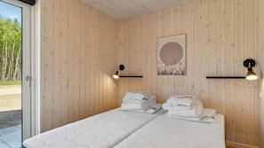 Ein Zimmer mit Holzvertäfelung, zwei Betten mit weißer Bettwäsche, einem gerahmten Kunstwerk und zwei Wandleuchten.