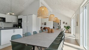 A modern kitchen with white cabinets, a long dining table, and a view of the outdoors.