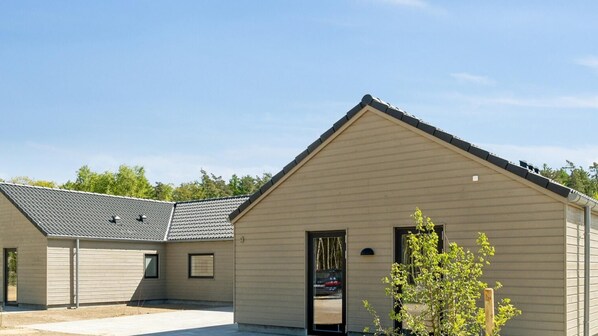 A modern building with a sloped roof, a garage door, and a small window.