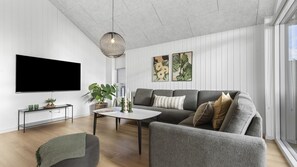 A modern living room with a flat-screen TV, grey sofa, coffee table, and a hanging pendant light. - VillaVilla 810 - Fjellerup, Østjylland (Glesborg)