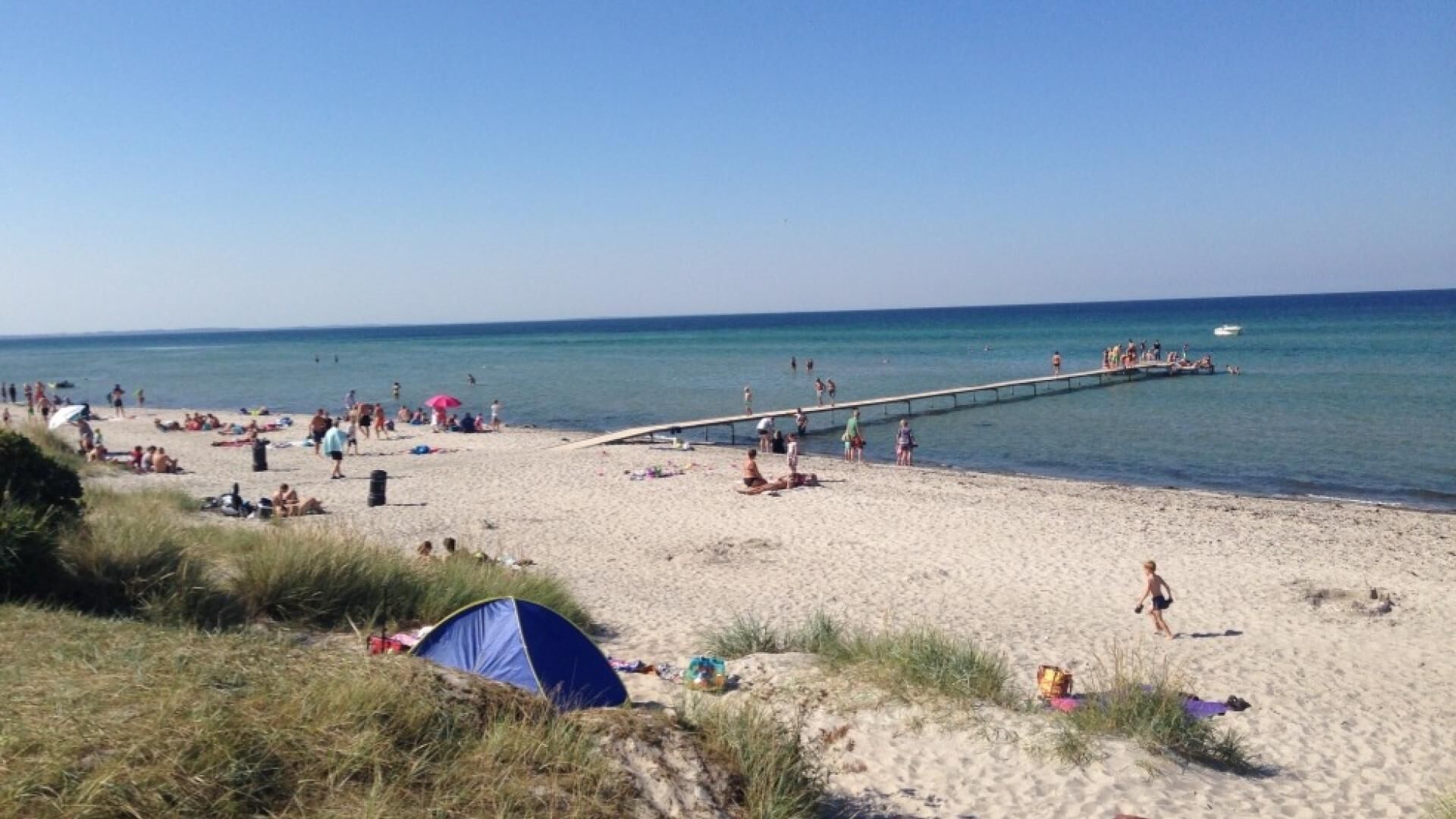 Une plage avec des gens, une jetée et une tente.