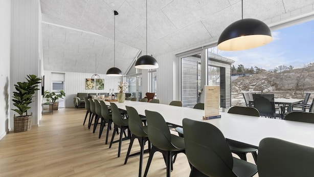 A modern dining area with a long table, chairs, pendant lights, and a view of the outdoors. - VillaVilla 810 - Fjellerup, Østjylland (Glesborg)