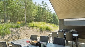 Un espace extérieur aménagé pour les repas, avec des chaises et une table en osier, offrant une vue sur une colline boisée.
