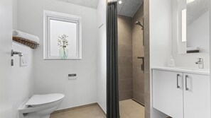 Un bagno moderno con un water, una doccia, un lavandino e uno specchio.