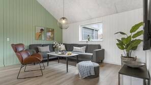 Un salon comprenant un canapé, un fauteuil, une table basse et une plante en pot.