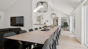 Un comedor moderno con una mesa larga, sillas negras y lámparas colgantes.