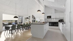 Een moderne keuken met witte kasten, een centraal eiland en hanglampen.