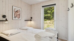 Une chambre avec deux lits, une œuvre d’art encadrée, des lampes fixées au mur et une vue sur la verdure grâce à une porte coulissante.