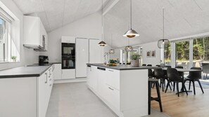 A modern kitchen with white cabinetry, a central island, and pendant lighting. - VillaVilla 817 - Fjellerup, Østjylland (Glesborg)