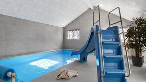 Ein Hallenbad mit einer blauen Rutsche, einer Leiter und einem Blumentopf.