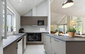A modern kitchen with a central island, built-in appliances, and large windows.